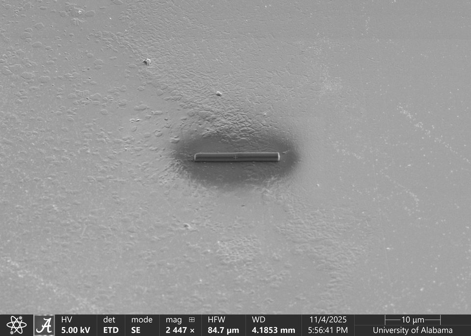 SEM image of a Pt protective strap deposited by ion beam on a flat surface, surrounded by a dark elliptical halo